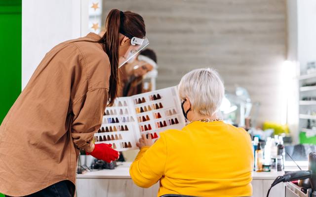 A hairstylist showing a client colour swatches in a salon